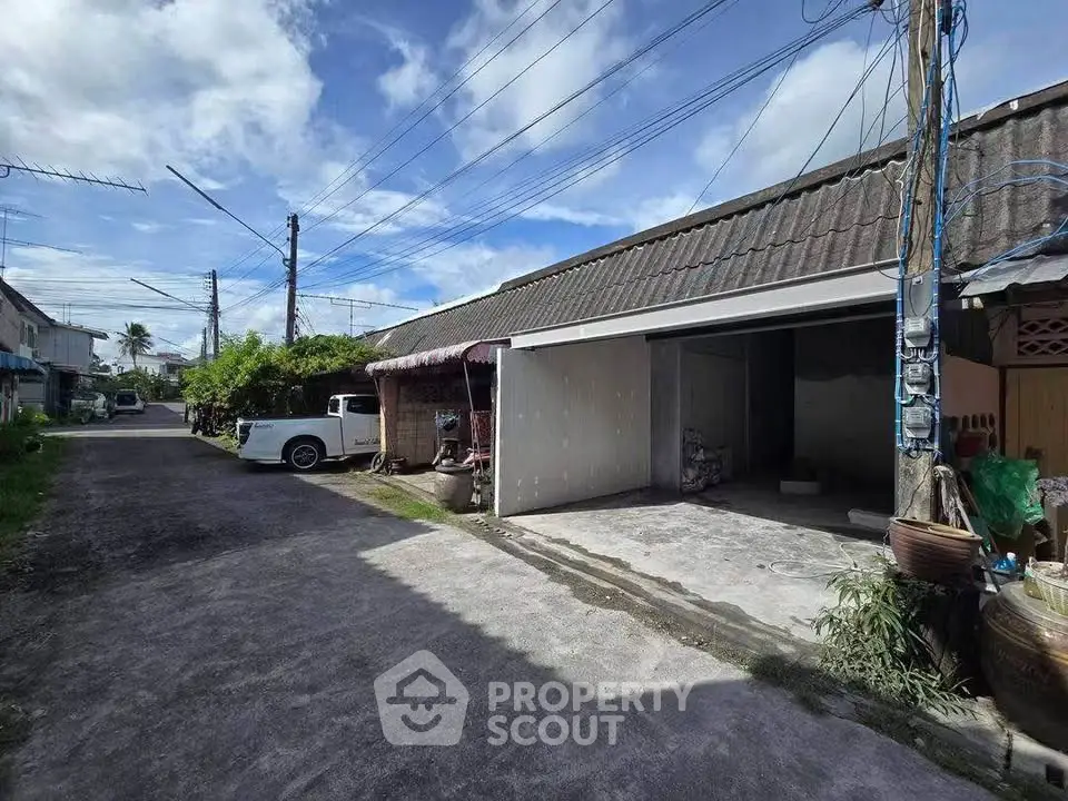 Charming residential street view with open garage and clear blue sky.