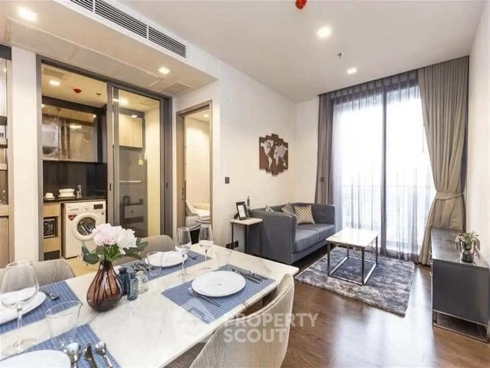 Modern living room with open kitchen, stylish decor, and natural light.
