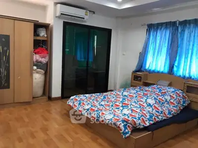 Spacious bedroom with wooden flooring and vibrant decor in a cozy home.
