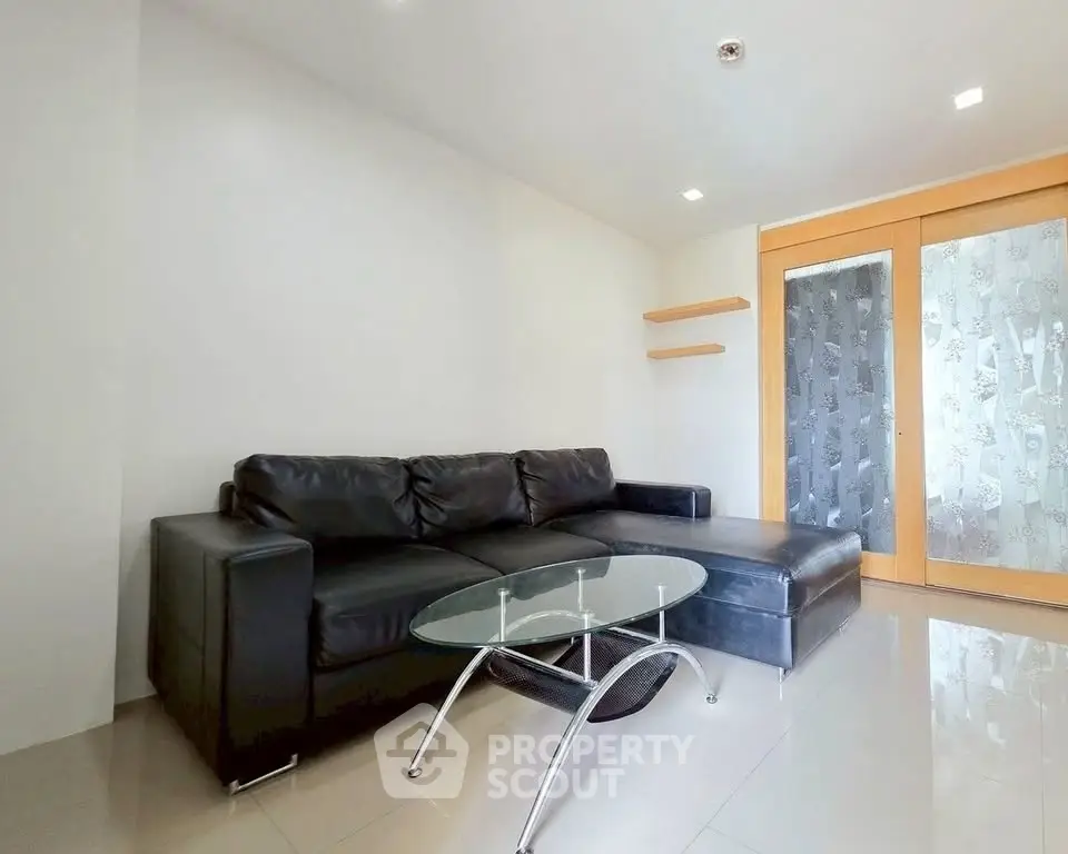 Modern living room with sleek black leather sofa and glass coffee table