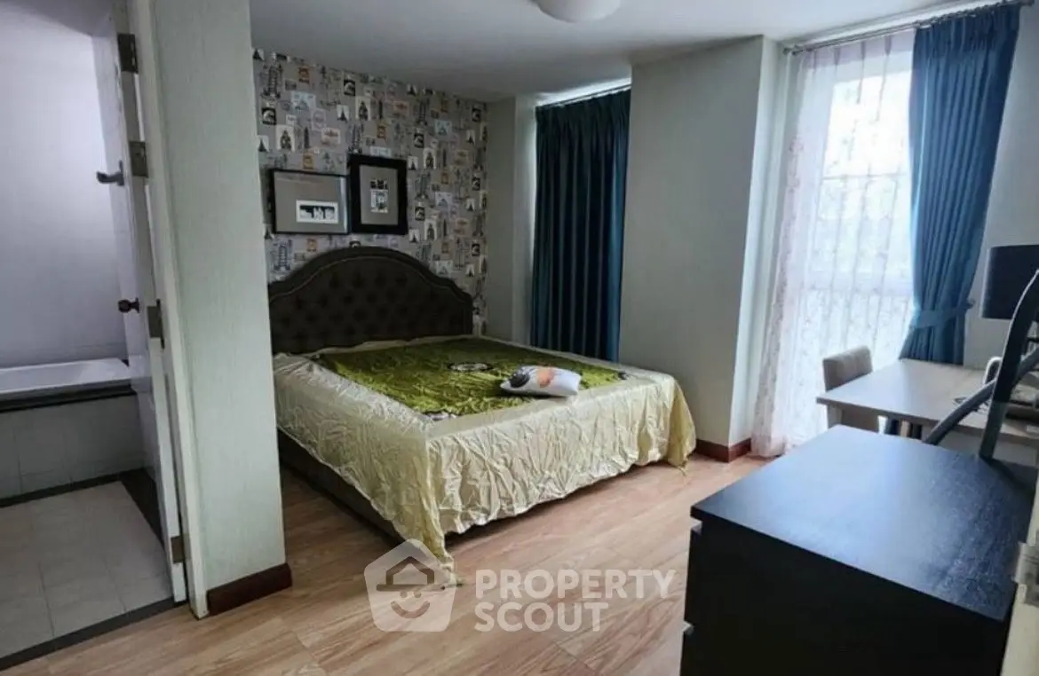 Cozy bedroom with stylish decor and natural light, featuring a comfortable bed and work desk.