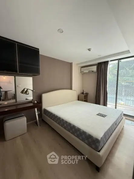 Spacious bedroom with modern decor and large window offering natural light and outdoor view.