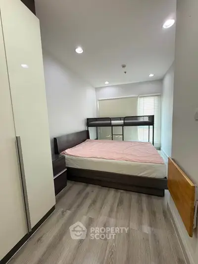 Modern bedroom with sleek design and ample natural light, featuring a stylish bed and contemporary flooring.