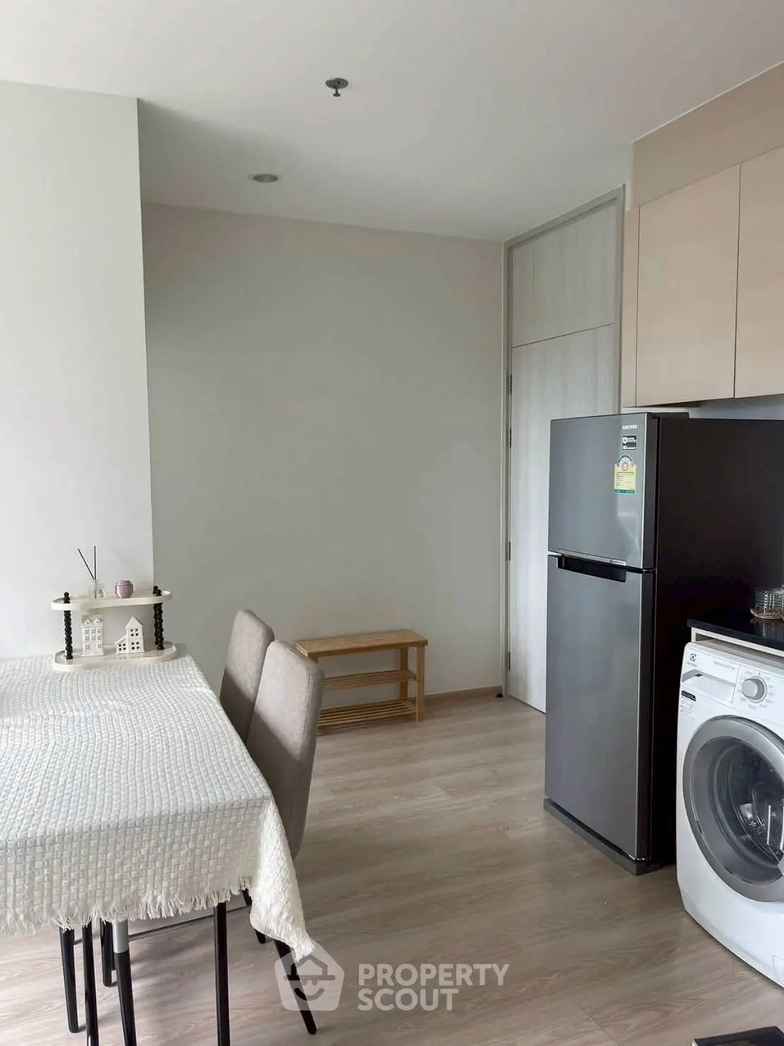Modern kitchen with dining area, featuring a fridge and washing machine, perfect for urban living.