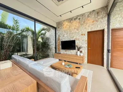 Luxurious living room with stone wall, modern furniture, and large glass windows.