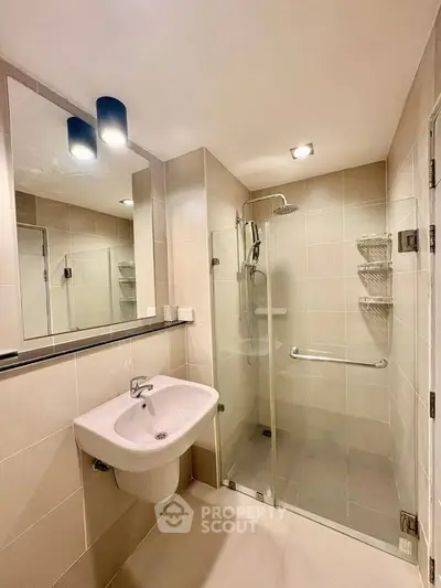 Modern bathroom with glass shower and sleek fixtures in contemporary apartment.