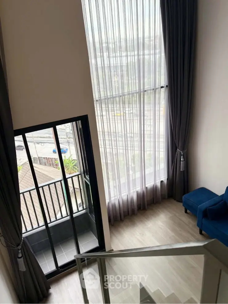 Modern duplex with floor-to-ceiling windows and small balcony offering city views.