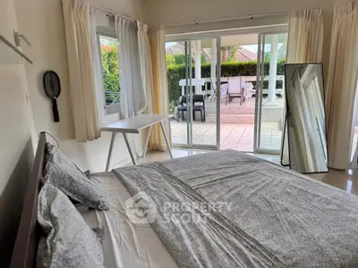 Spacious bedroom with large windows opening to a private patio, offering serene outdoor views.