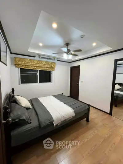 Cozy bedroom with modern ceiling fan and wooden flooring, perfect for relaxation.