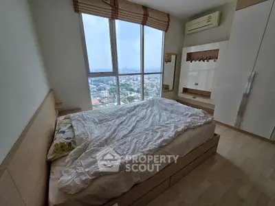 Spacious bedroom with large window offering stunning city views, featuring modern furnishings and ample natural light.