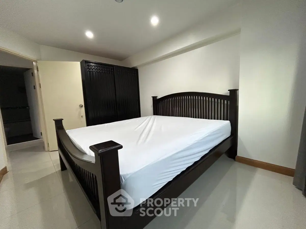 Spacious bedroom with elegant dark wood bed and wardrobe, perfect for a cozy retreat.