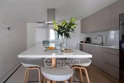 Modern kitchen with sleek design and open layout, featuring a stylish island and contemporary stools.