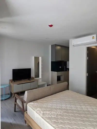 Modern studio apartment with open layout, featuring a cozy living area and compact kitchen.