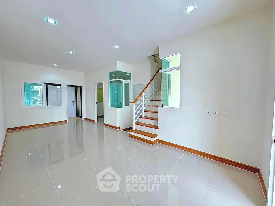 Spacious modern living room with glossy tile flooring and elegant staircase