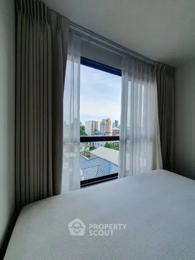 Bright bedroom with large window offering city view and natural light