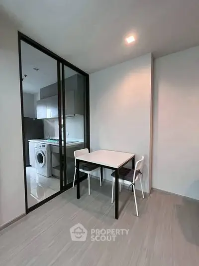 Modern kitchen with washing machine and dining area in sleek apartment.