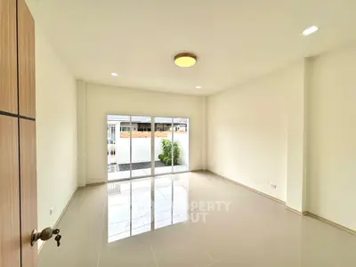 Spacious and bright living room with large windows and glossy tiled floors, perfect for modern living.