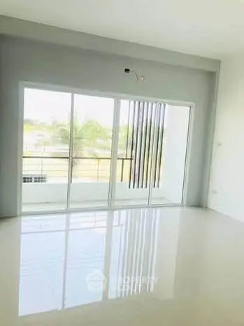 Spacious modern living room with large glass doors and balcony view