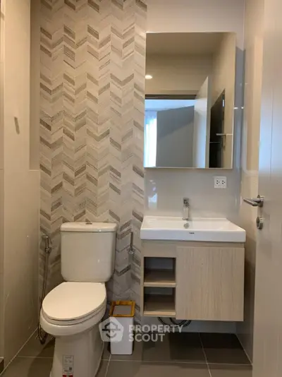 Modern bathroom with stylish chevron tile accent wall and sleek fixtures.
