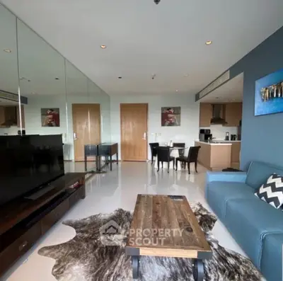 Modern living room with stylish decor and open kitchen layout, featuring a cozy blue sofa and rustic coffee table.