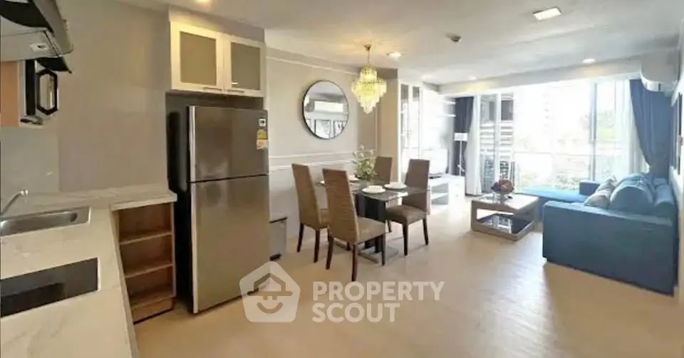 Spacious open-plan living room with modern kitchen and dining area, featuring large windows and elegant decor.