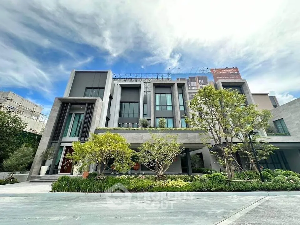 Modern multi-story building with lush landscaping and contemporary design elements.