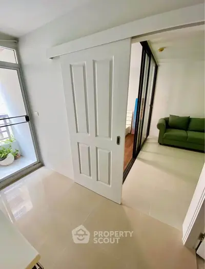 Modern apartment with sliding doors and balcony access, featuring a cozy green sofa.