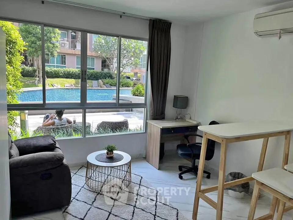 Modern living room with pool view, featuring cozy seating and a stylish workspace.