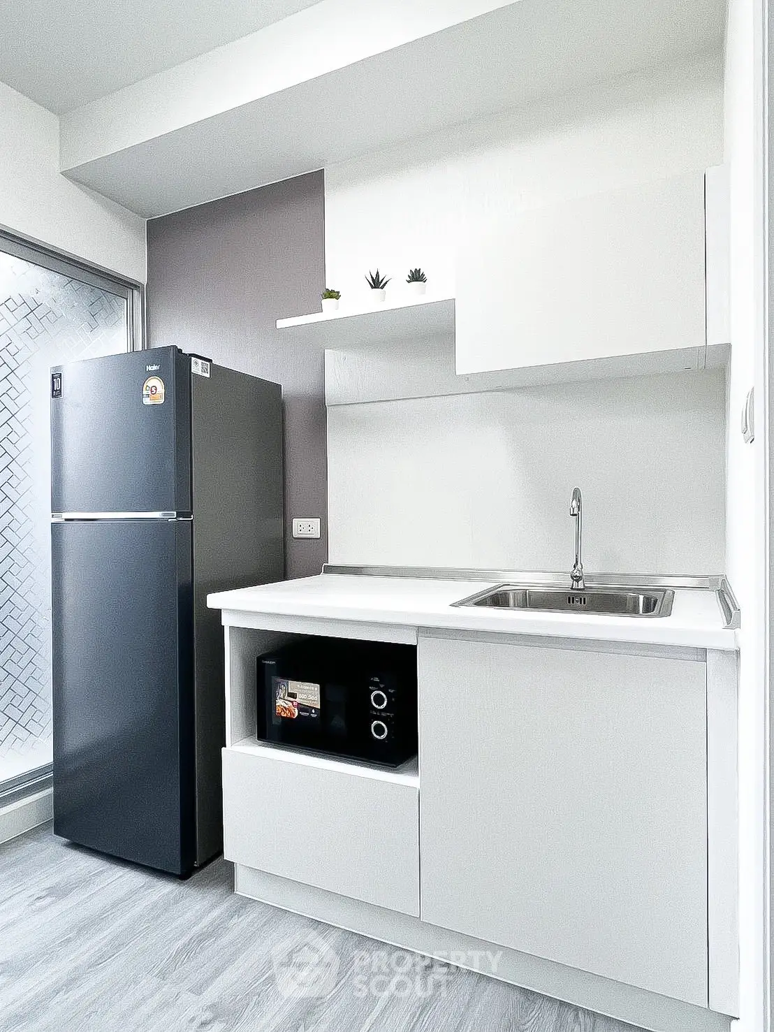 Modern kitchen with sleek white cabinets and stainless steel appliances in a compact layout.
