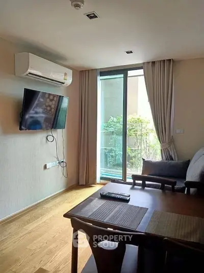 Modern living room with air conditioning and balcony view, featuring a wall-mounted TV and elegant dining area.
