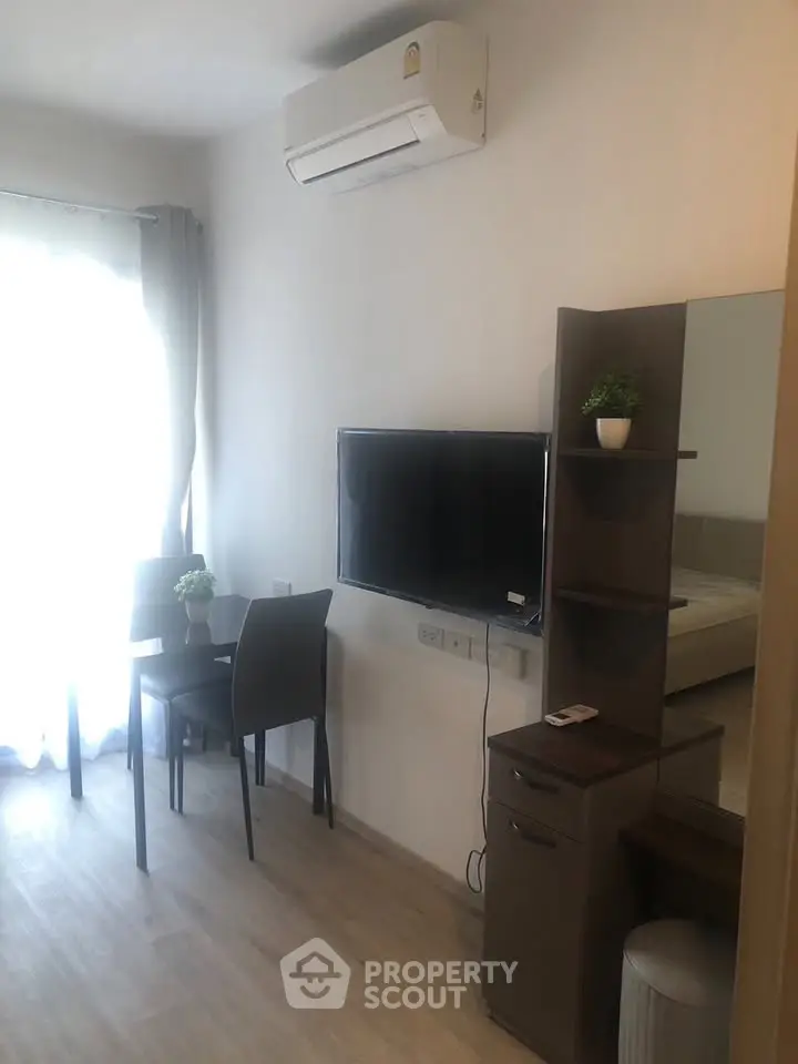 Modern living room with wall-mounted TV and air conditioning in a cozy apartment.