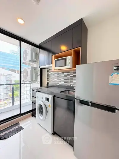 Modern kitchen with sleek appliances and city view, featuring washing machine and microwave.
