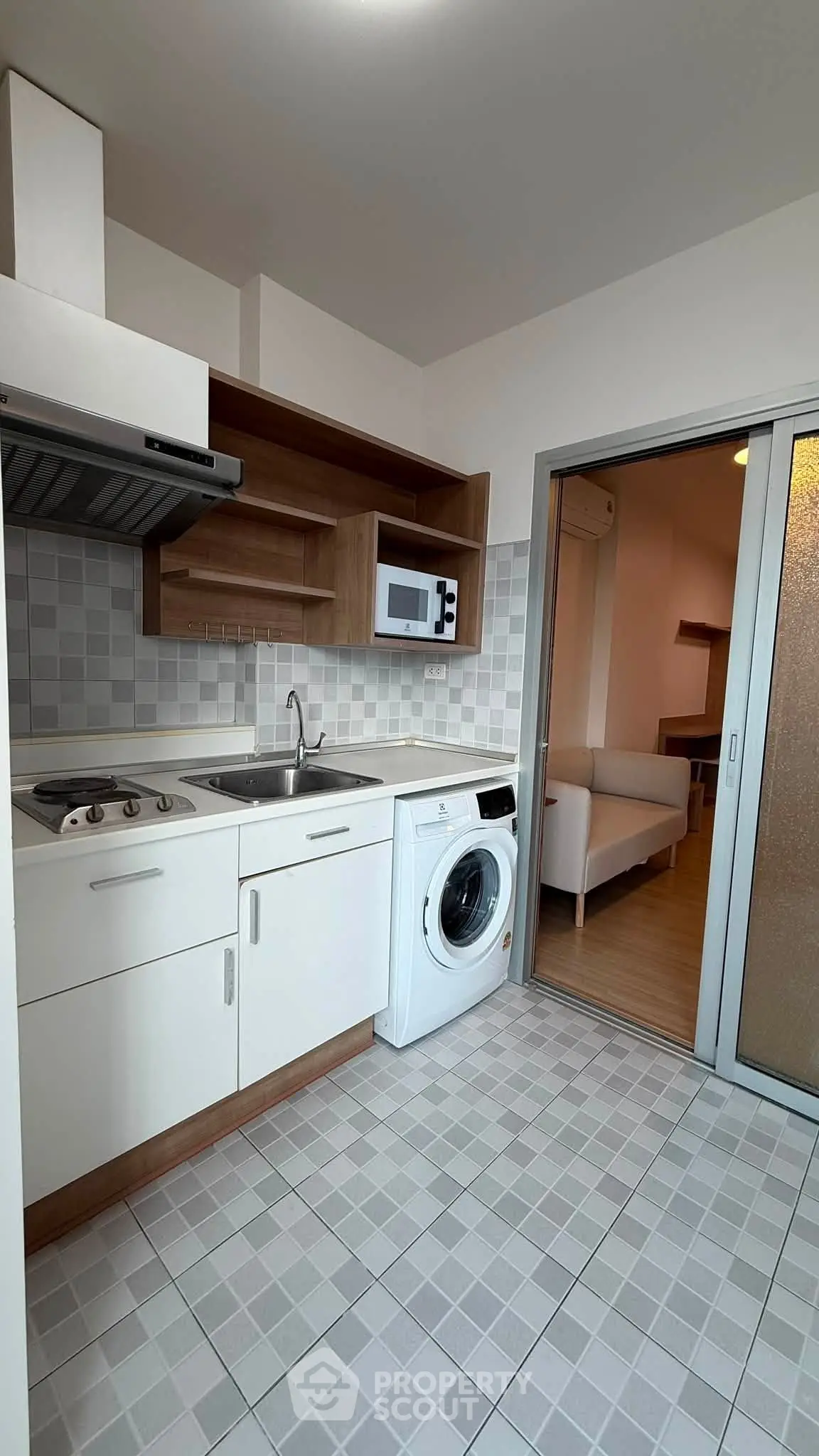 Modern kitchen with washing machine and open layout leading to cozy living area.