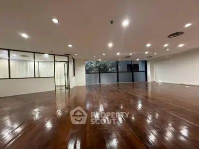 Spacious polished hardwood floor office space with large windows and modern lighting.