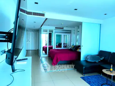 Modern studio apartment with sleek design and mirrored accents, featuring a cozy bed and stylish seating area.