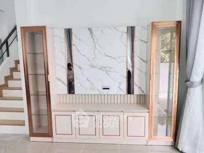 Elegant living room with modern marble accent wall and stylish glass cabinets