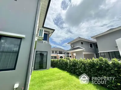 Modern suburban homes with lush green lawns and clear blue sky.