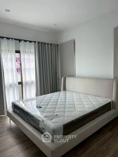 Spacious bedroom with modern bed and natural light through large windows.