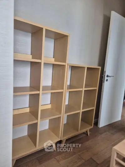 Modern wooden shelving units in a stylish interior space with open door and hardwood flooring.