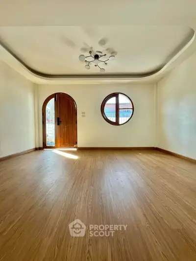 Spacious living room with unique round window and elegant wooden flooring