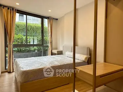Spacious bedroom with large window and modern furnishings in a stylish apartment.