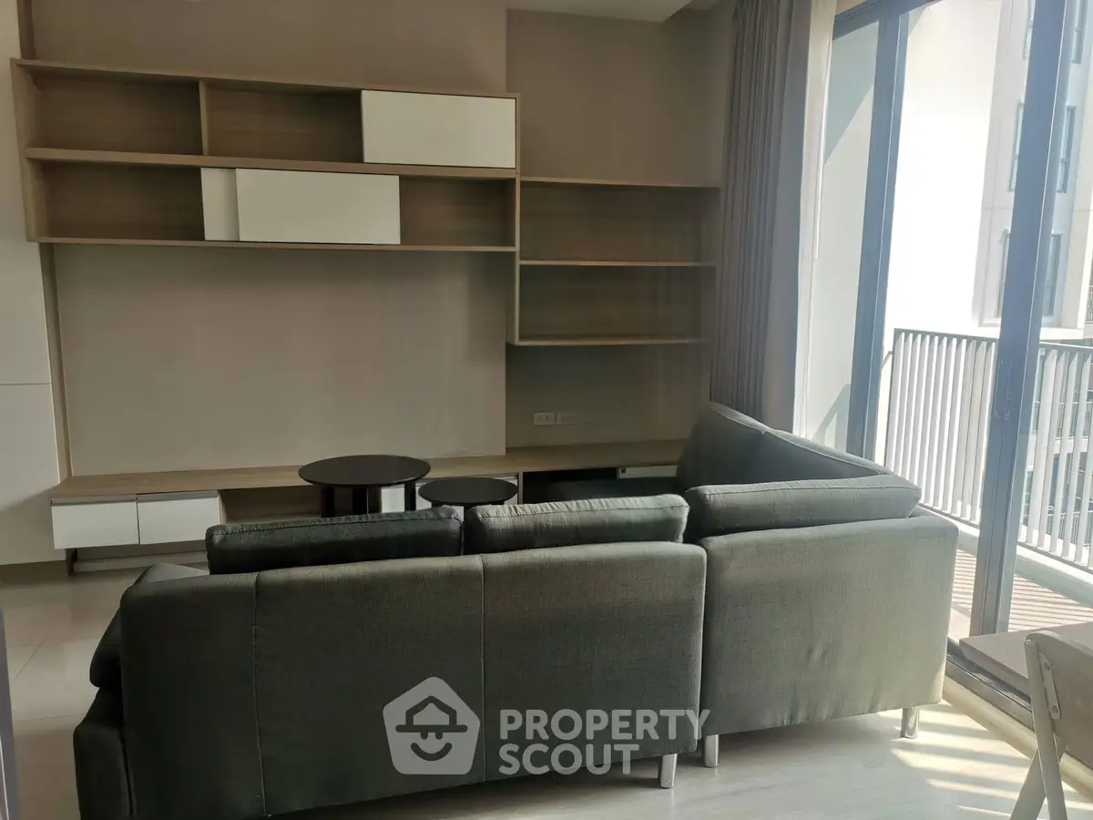 Modern living room with sleek shelving and large windows opening to a balcony.