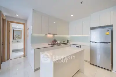 Modern kitchen with sleek white cabinetry and stainless steel appliances in a bright apartment.
