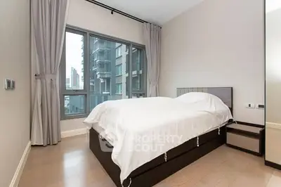 Modern bedroom with large window and city view, featuring sleek design and neutral tones.