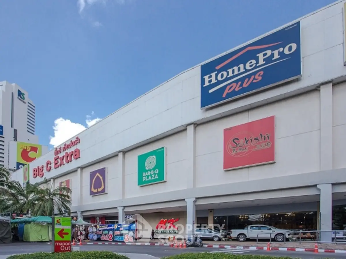Commercial building exterior with multiple retail store signs and parking area.