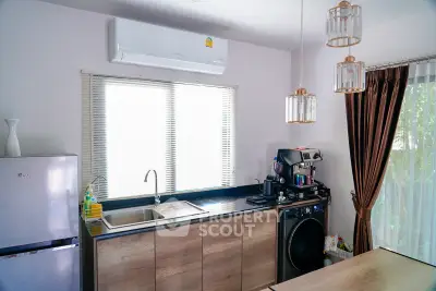 Modern kitchen with sleek appliances and natural light, featuring a washing machine and stylish lighting fixtures.