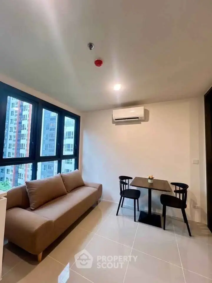 Modern living room with large windows, cozy sofa, and dining area in a high-rise apartment.