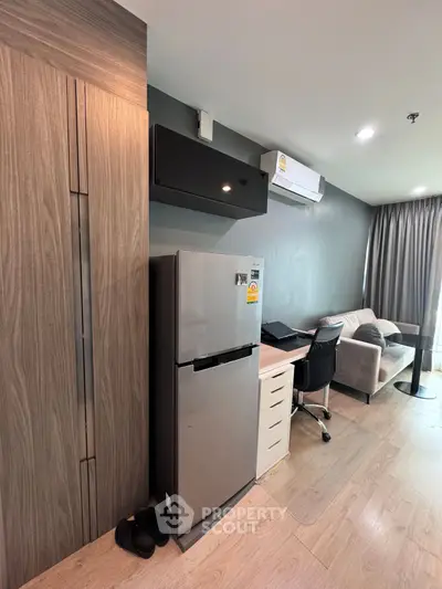 Modern apartment interior with sleek fridge, cozy sofa, and stylish workspace.