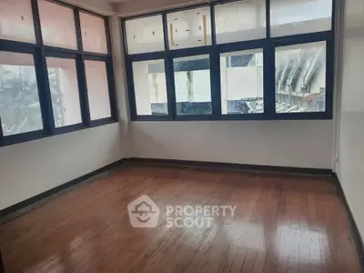 Spacious room with large windows and wooden flooring, ideal for natural light lovers.