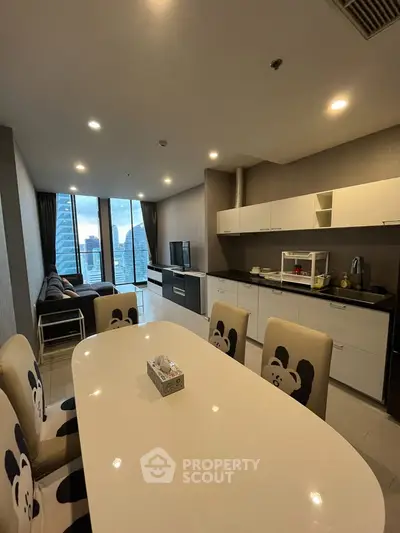 Modern open-layout kitchen and living room with city view, stylish decor, and ample natural light.